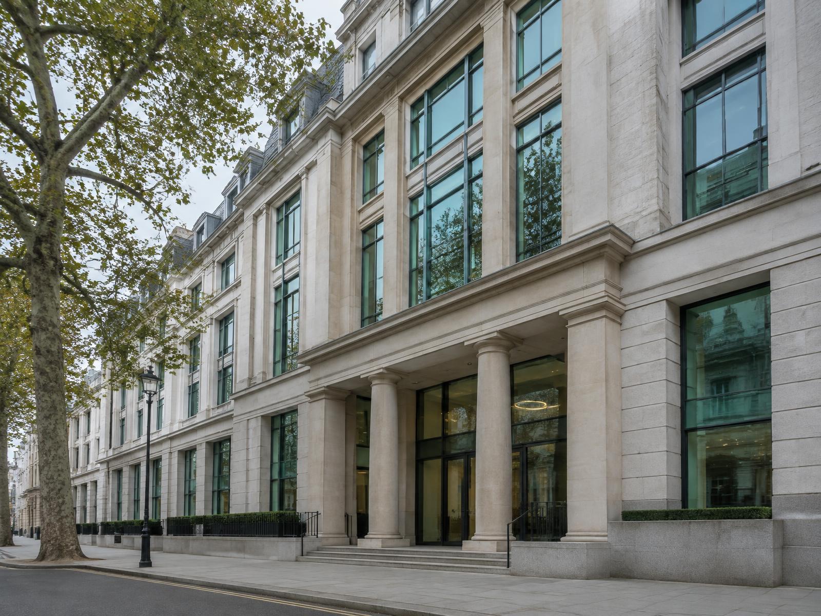 Central London office building with stone facade and green glass under overcast light